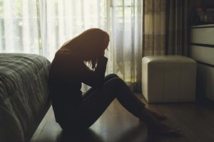 teenage girl sitting on floor of darkened bedroom finally understanding self harm and the dangers