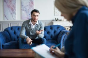 therapist talking with male patient combining counseling with cognitive-behavioral therapy