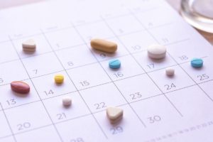 image of different pills placed upon specific days of a desk calendar as a reminder to not let medication management be taboo