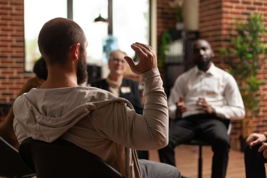 image of a group therapy session where a young man is asking what are the benefits of psychiatry and counseling