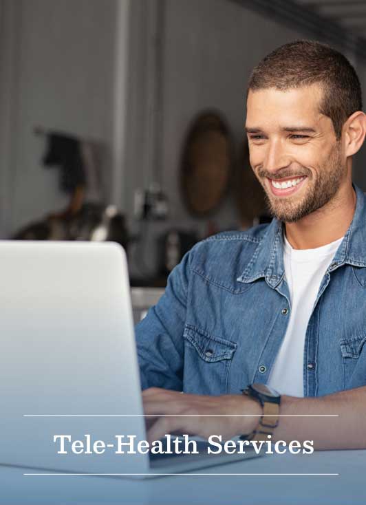 image of a young man smiling as he interacts with a laptop and the words tele-health services are across the bottom of the picture