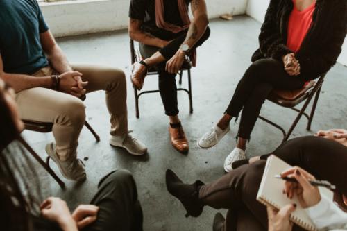 shot of the feet of a seated circle of people in a group counseling session