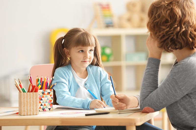 young female child engages in art therapy with adult female therapist