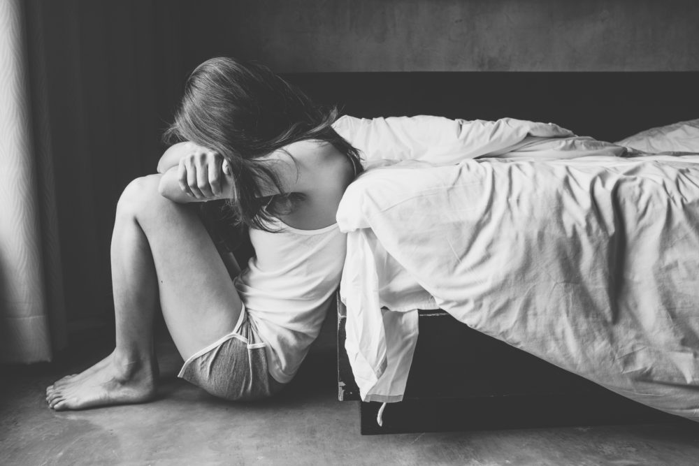 black and white photo of depressed woman sitting alone in bedroom