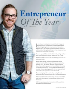Man wearing glasses and a checkered blue shirt with dark vest, featured in a magazine article layout