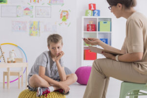 bored male child being addressed by female therapist