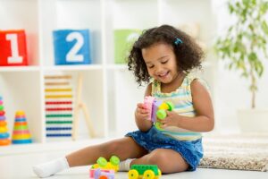 small female child smiling as she interacts with toys during play therapy