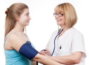 female medical professional taking blood pressure of female patient
