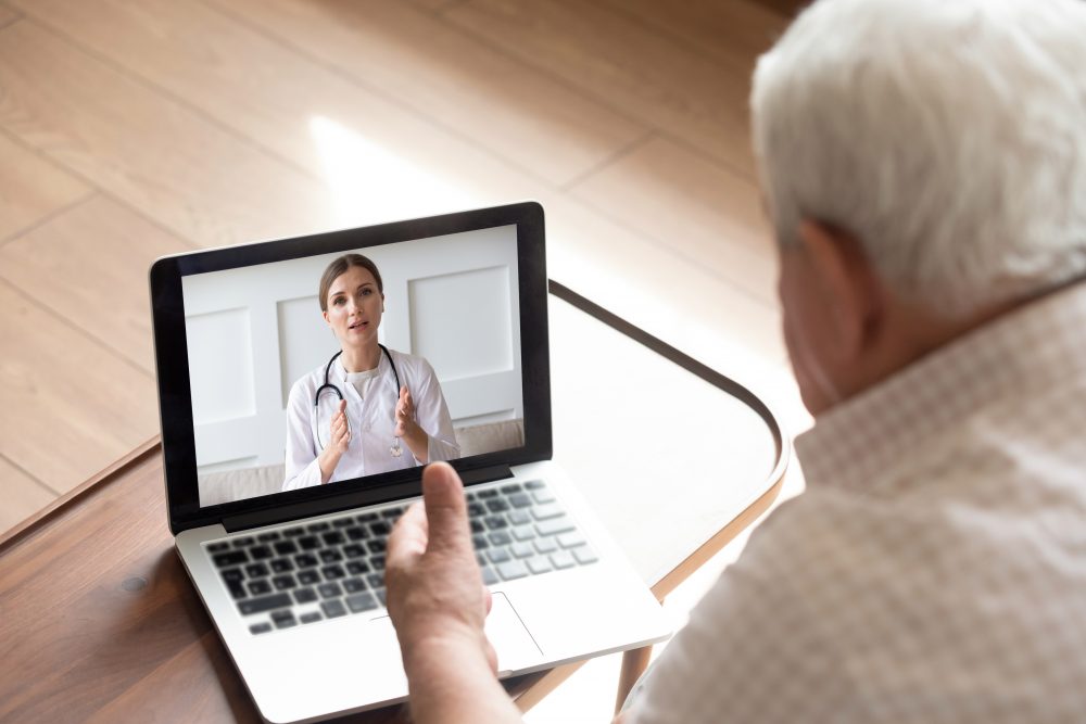 older man talking to female therapist via laptop for telemedicine session