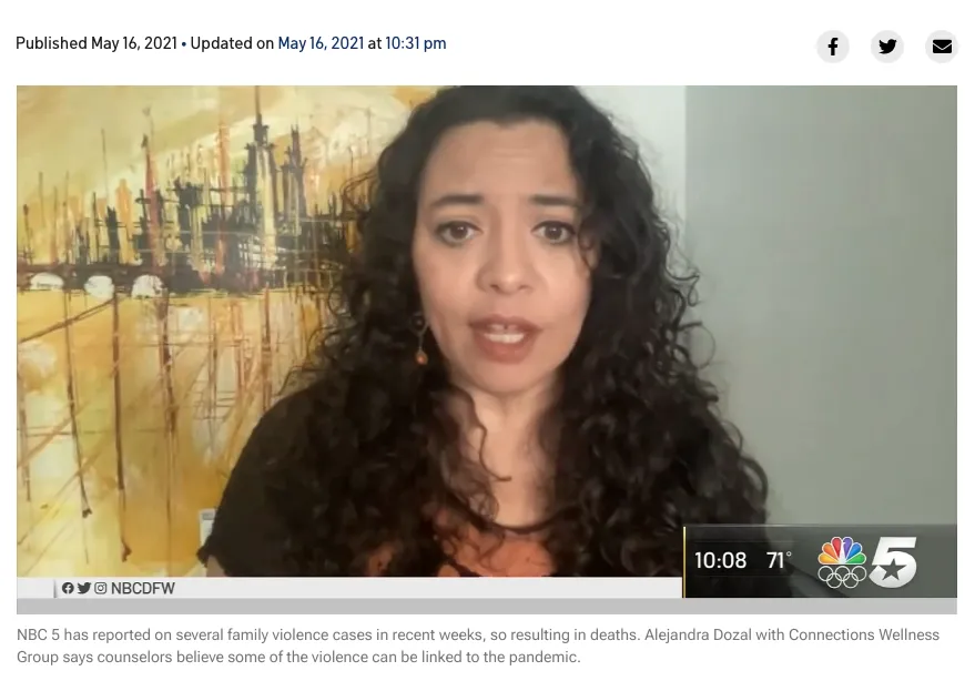 Woman with long dark curly hair speaking on video call, wearing dark clothing, interior background with artwork