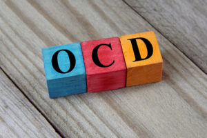 image of three colored children's blocks each with a letter and neatly arranged spelling out OCD symbolizing 5 signs your loved one has OCD