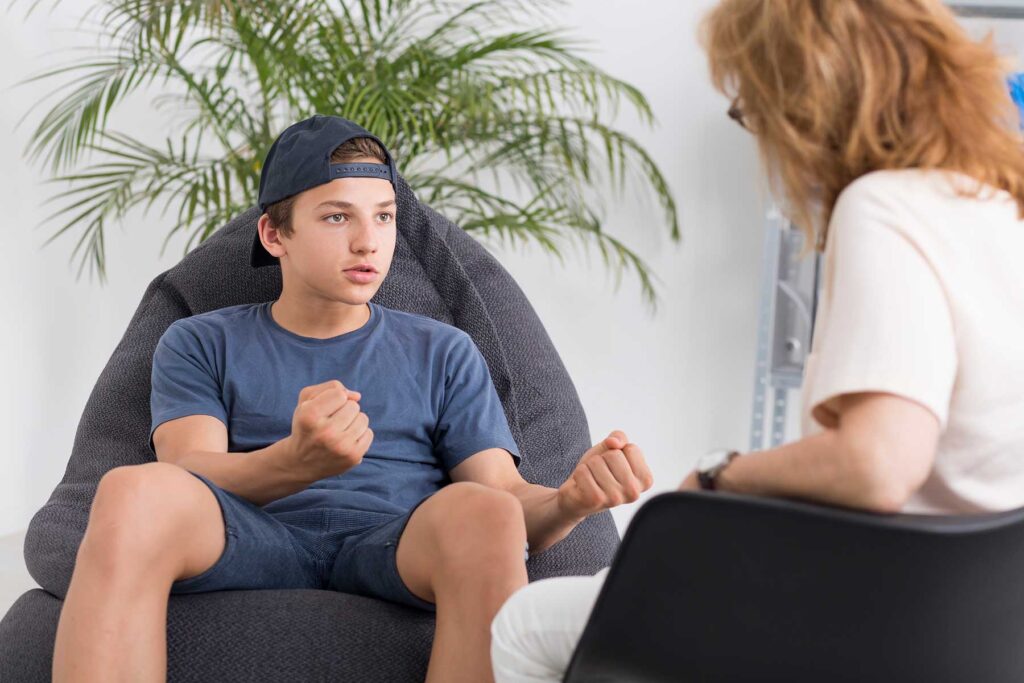 therapist in office setting talking to teenage boy about finding mental health treatment for teens in mansfield, texas