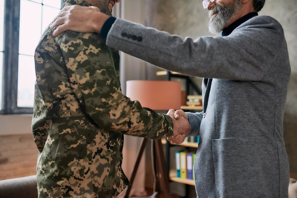 older male therapist shaking the hand of a soldier in battle fatigues as an example of PTSD in veterans and finding treatment and support for them