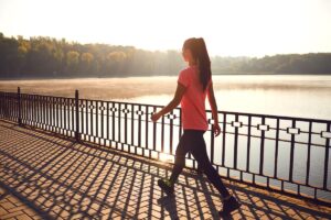 young woman walking along a pier on a sunny day enjoying one of 5 outdoor activities to improve your mood