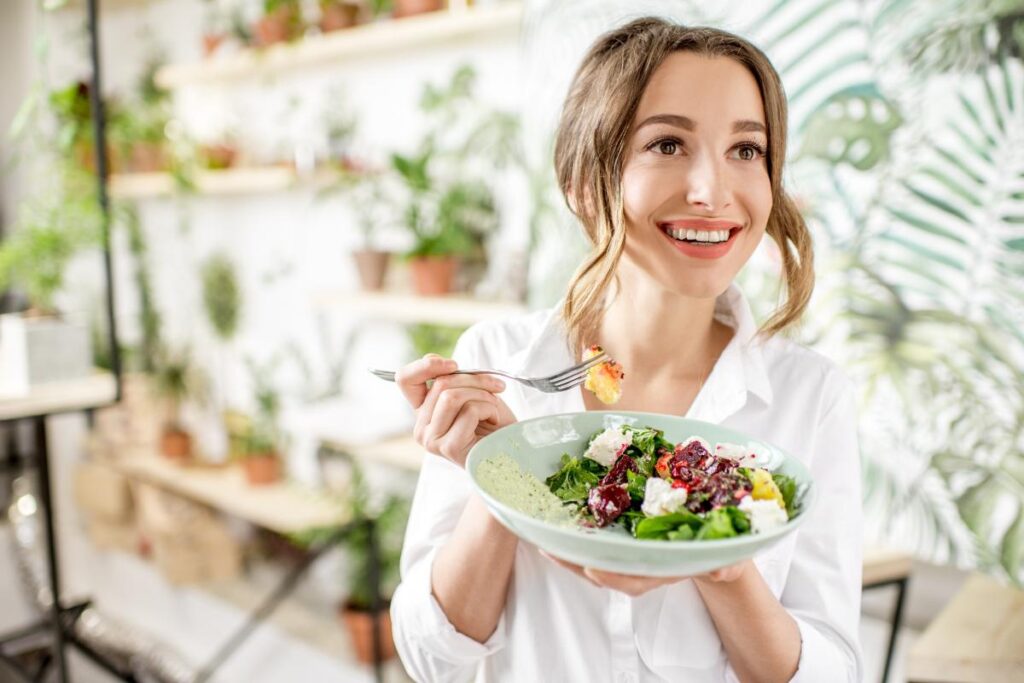 smiling young woman holding plate of fresh fruits and vegetables demonstrating why nutrition is so important to your mental health