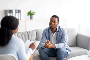 young man smiling as he discusses dialectical behavior therapy with his therapist