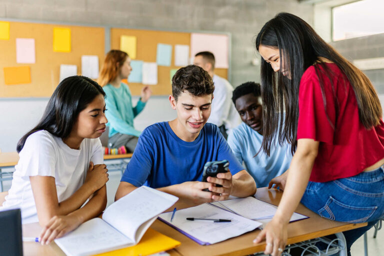 Connections Wellness Group—teens studying in a classroom, smiling and looking at a phone together